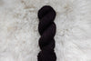 A skein of natural fiber, DK weight yarn has been hand dyed dark burgundy.