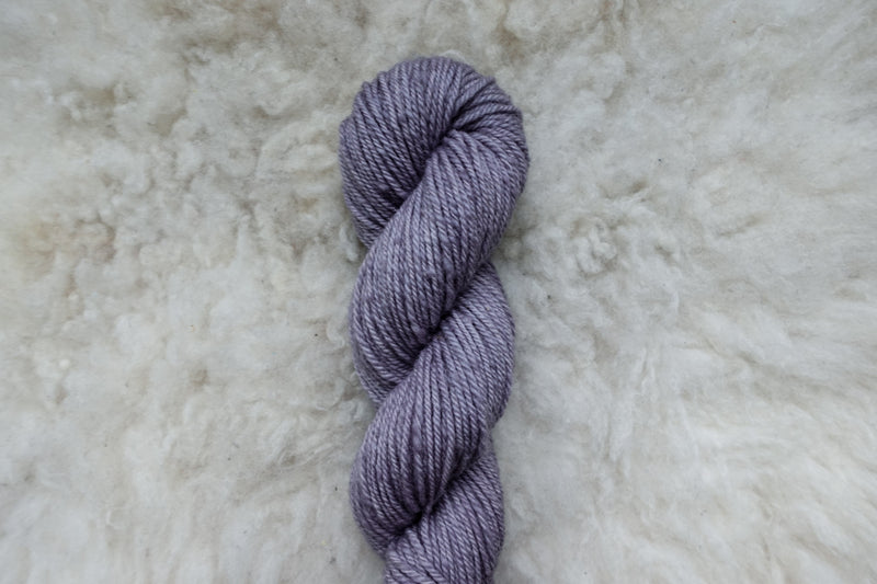 A skein of yarn has been naturally dyed a light purple. It's pictured from above.