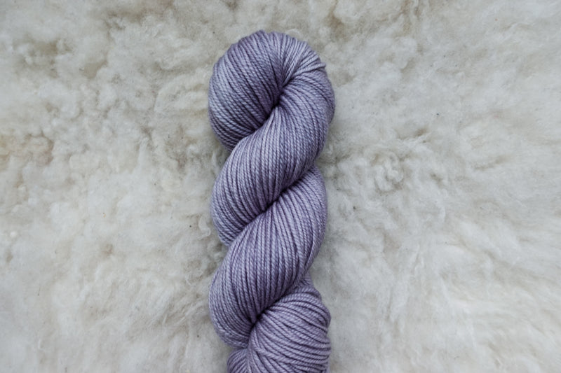 A light purple skein of natural fiber, worsted weight yarn is pictured from above.