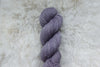 A natural fiber skein of light purple yarn is pictured from above.