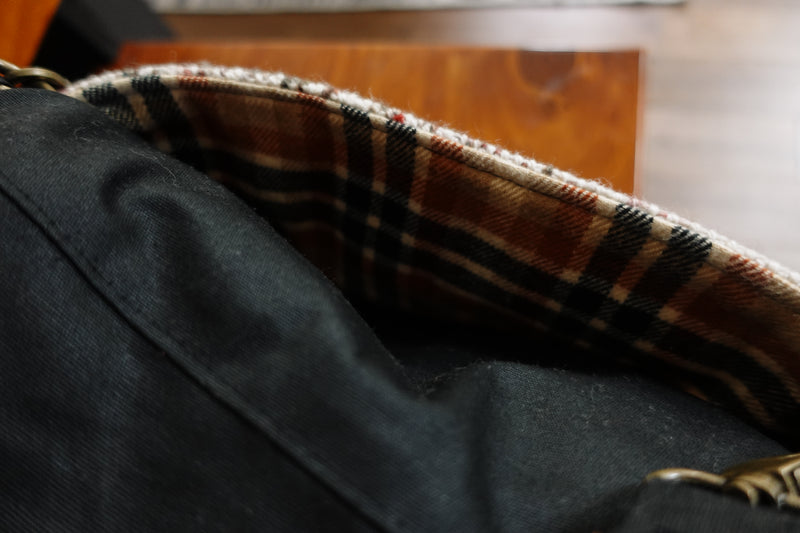 A close up of the precise stitch on the knitting project bag, showing where the woven white speckled fabric is sewn to the orange cotton plaid interior.