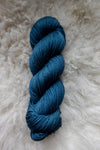 Seen from above, an indigo blue skein of naturally dyed yarn lays on sheepskin.