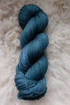 Seen from above, an indigo blue skein of naturally dyed yarn lays on sheepskin.
